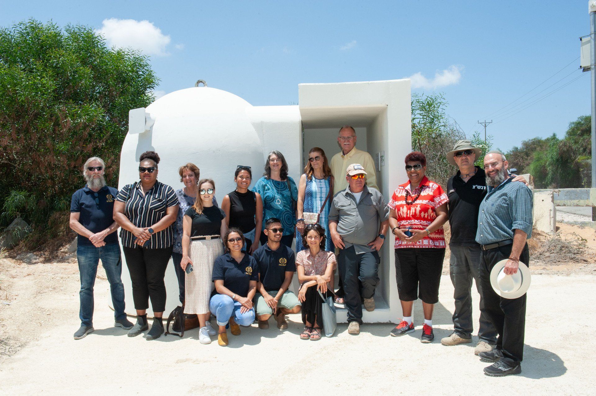 A group of people are posing for a picture in front of a white building.