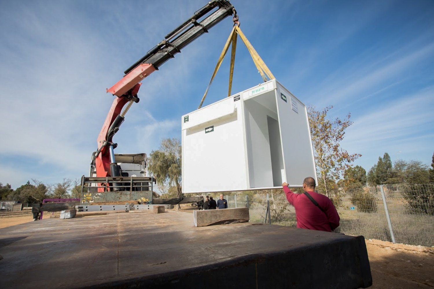 A crane is lifting a white box into the air.