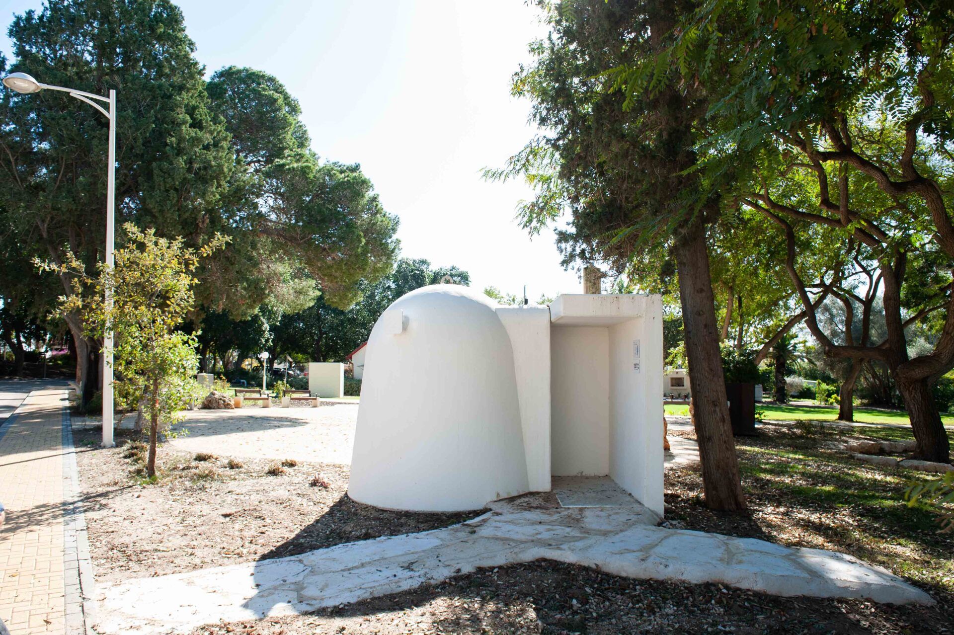 A white dome shaped Shelter in the middle of a park