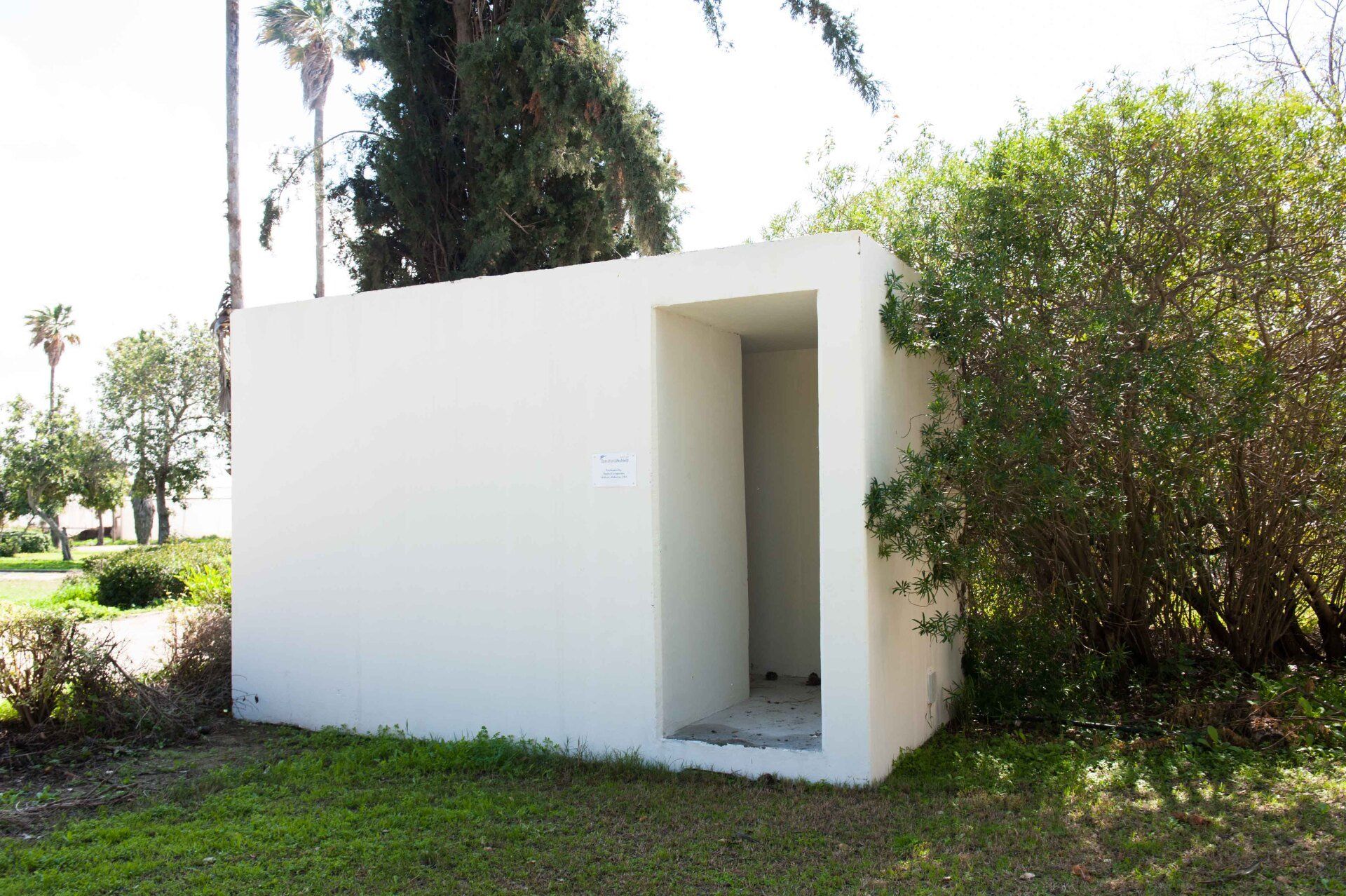A small white building in the middle of a grassy field