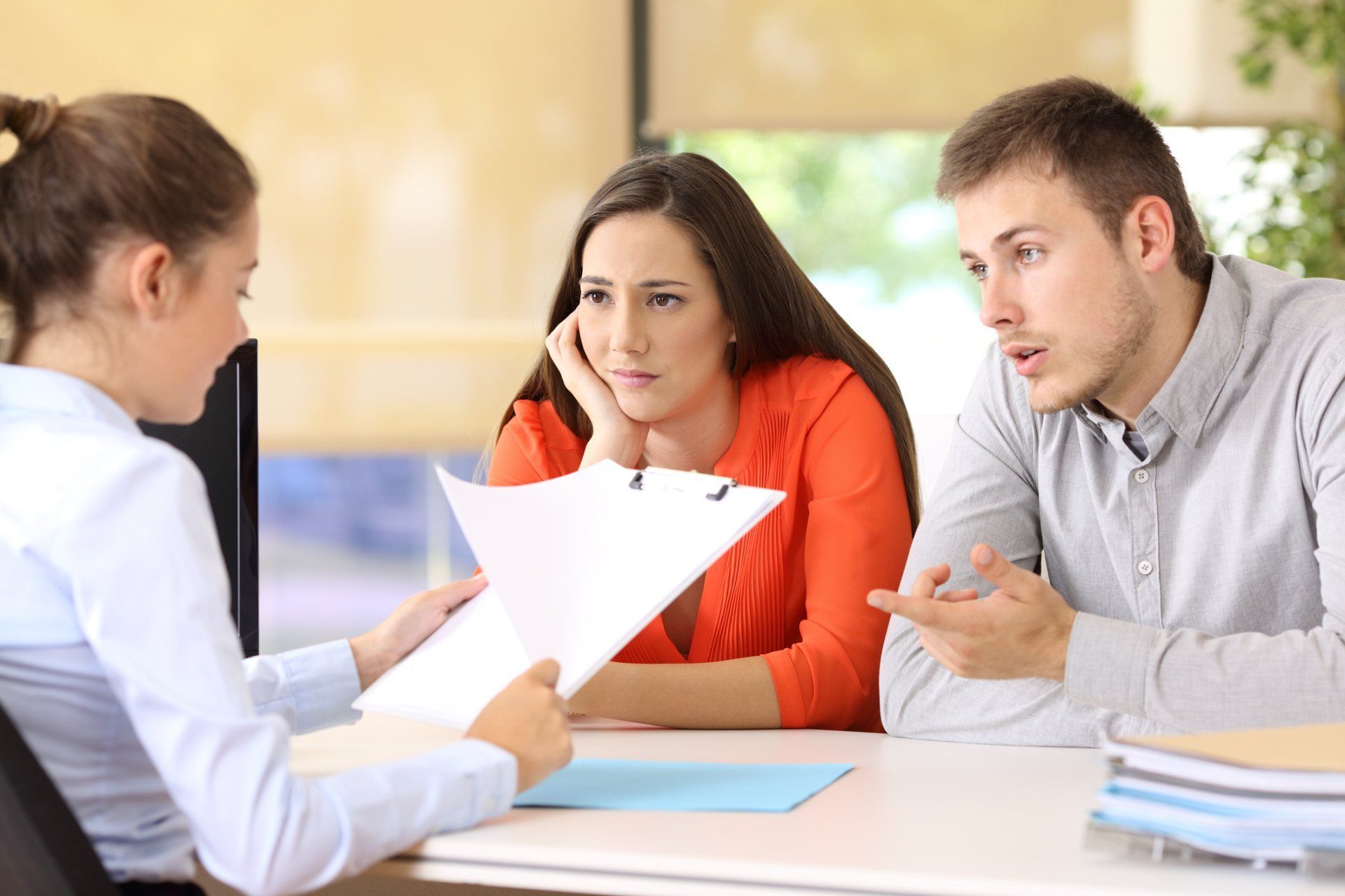A man and a woman are sitting at a table talking to a woman.