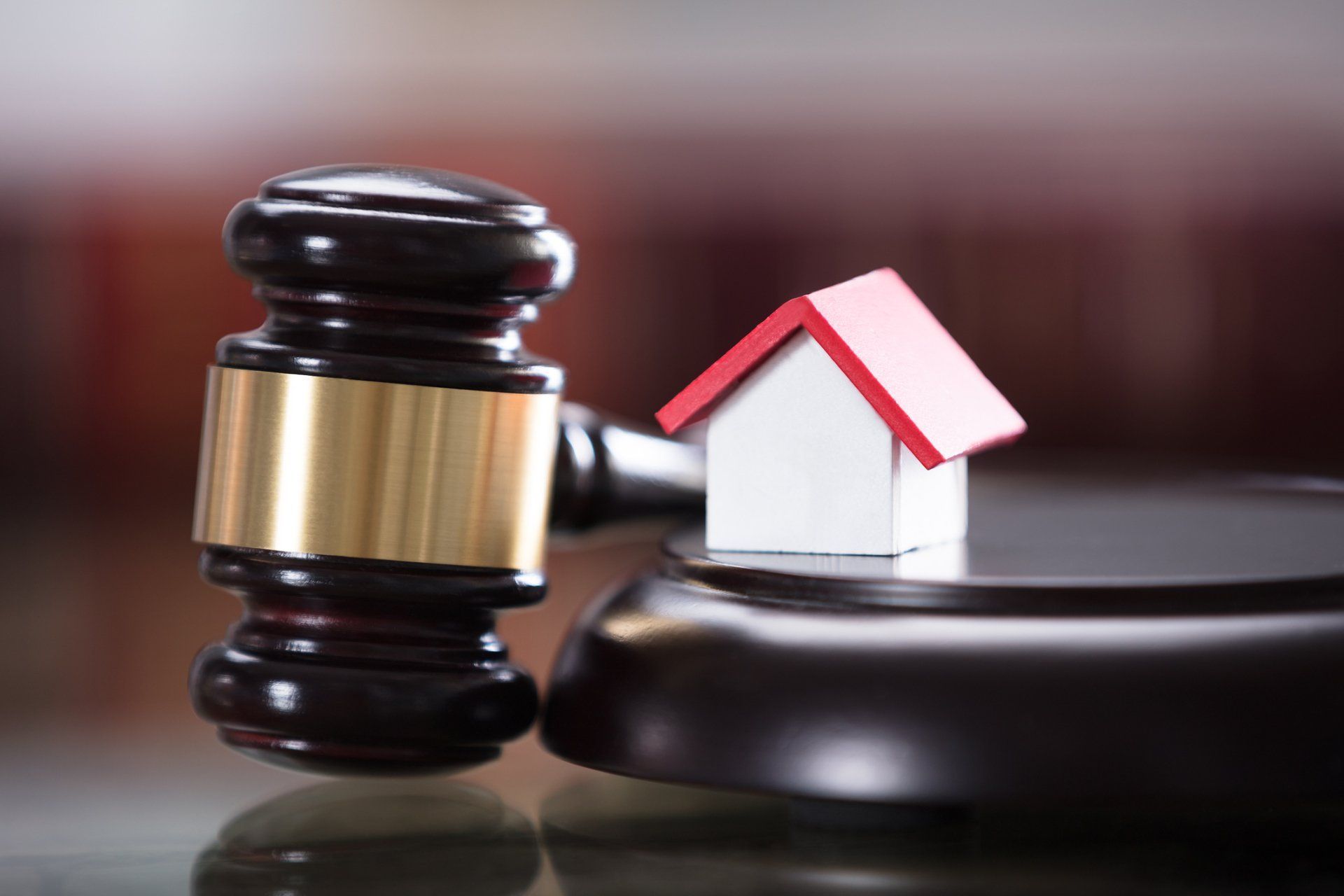A small house is sitting on top of a wooden gavel.