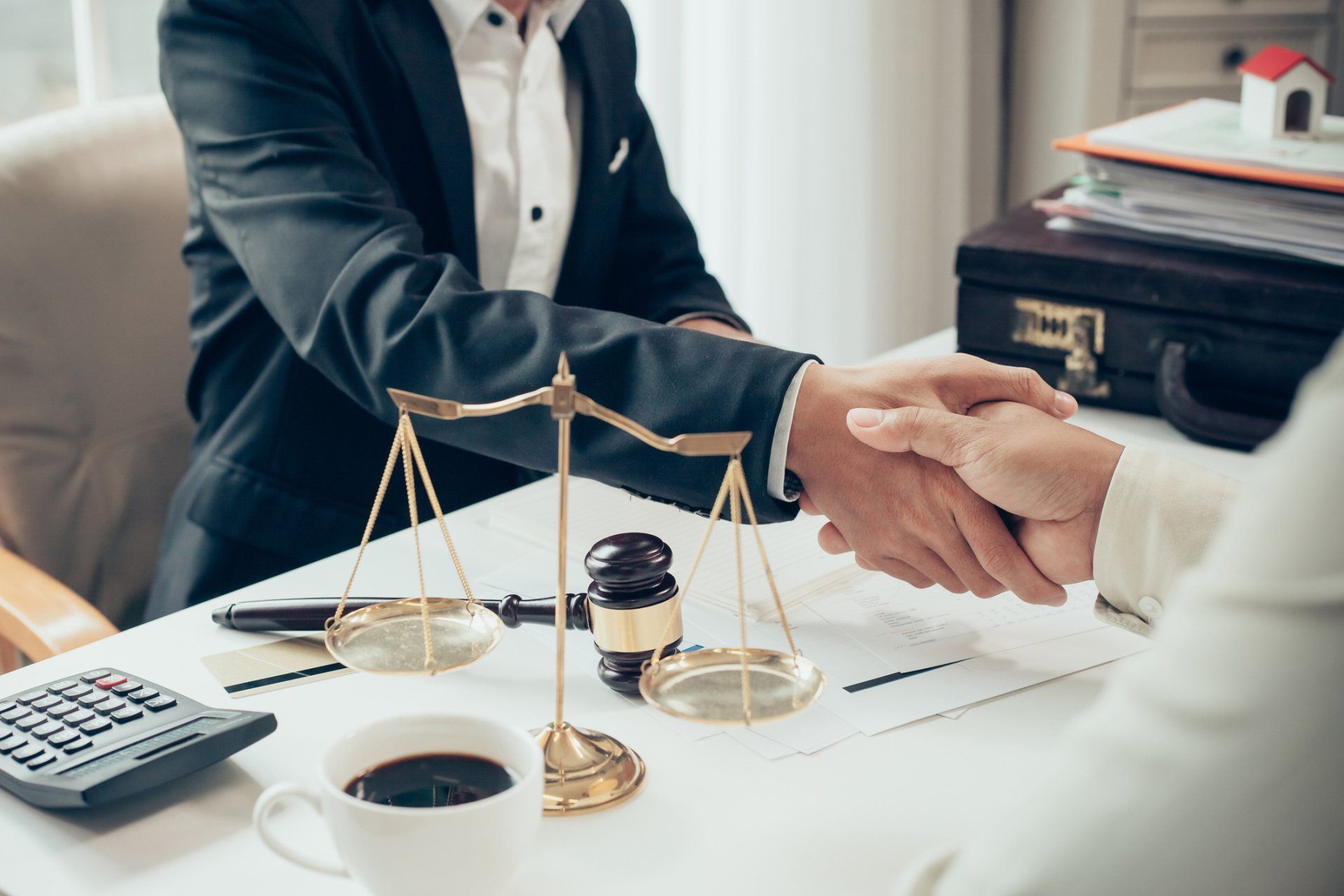 A man and a woman are shaking hands at a table with scales of justice.