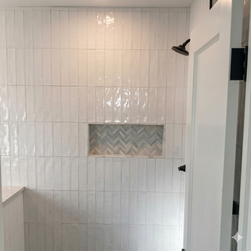 A white, vertical-tiled shower wall with a recessed niche featuring a light grey herringbone pattern.