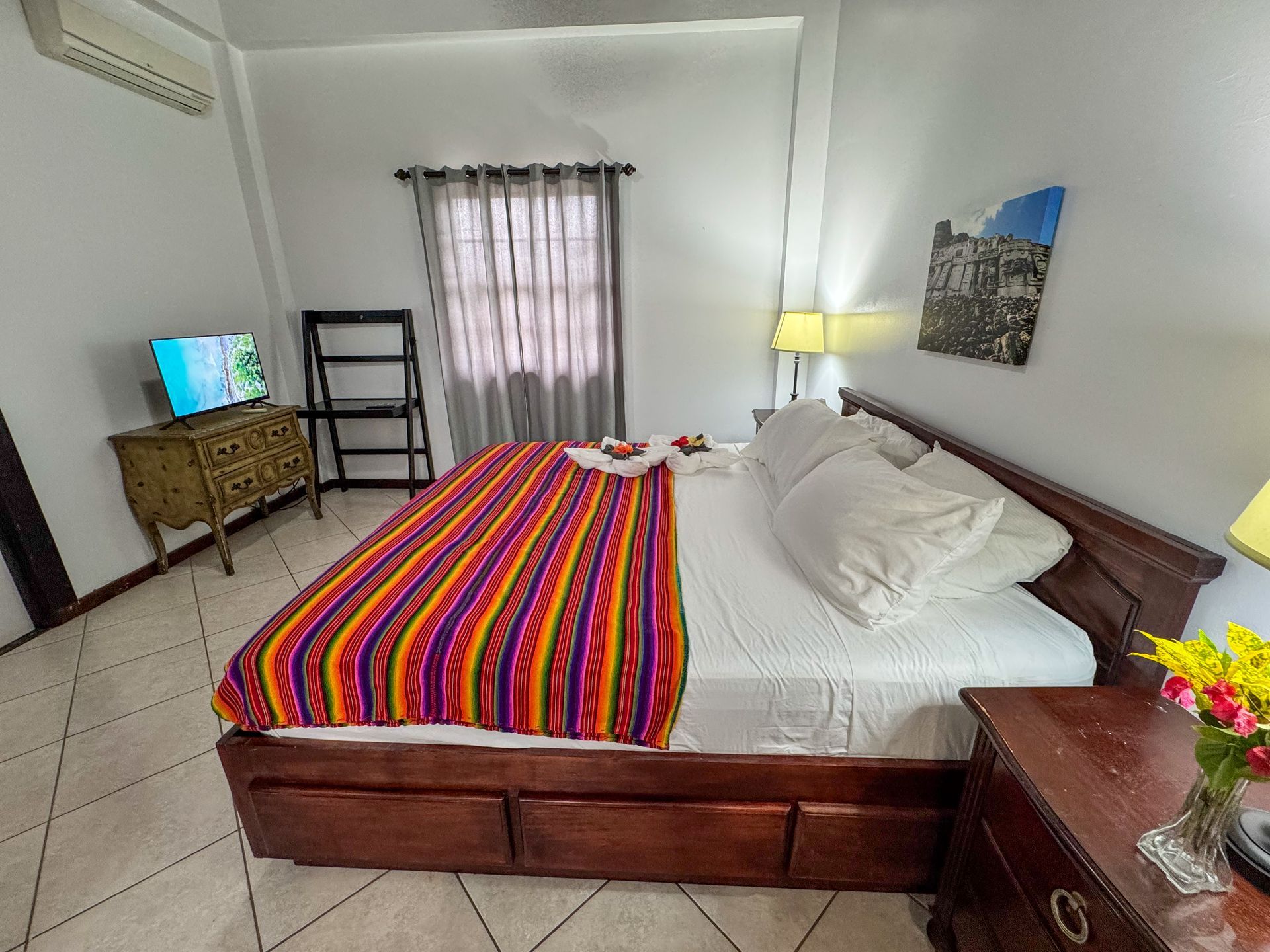 A bedroom with a king size bed , nightstand , television and dresser.