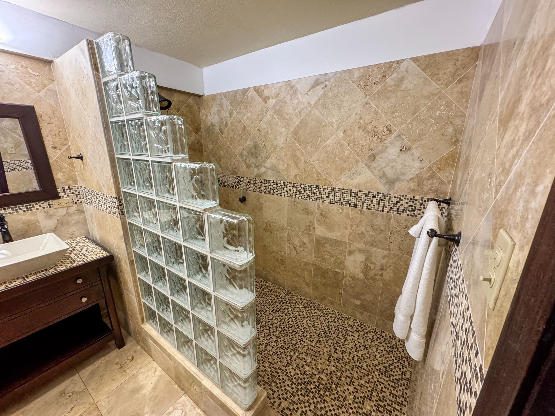 A bathroom with a walk in shower and a sink.