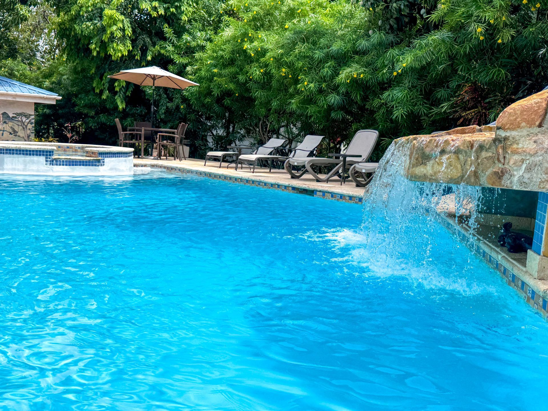 Outdoor pool with a waterfall and waterslide at Caribbean Shores Bed & Breakfast in Hopkins, Belize.