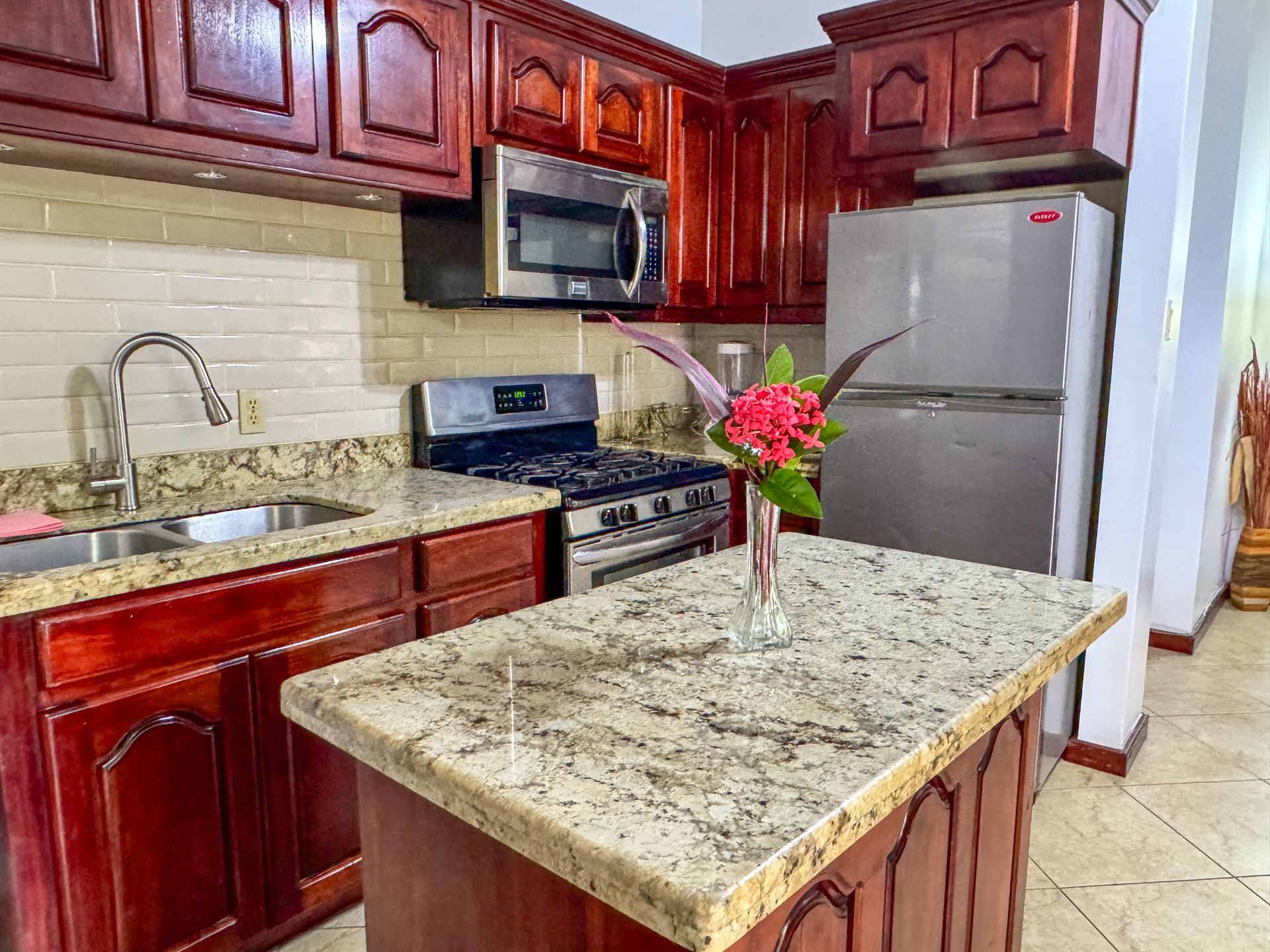 A kitchen with wooden cabinets , granite counter tops , stainless steel appliances and a large island.