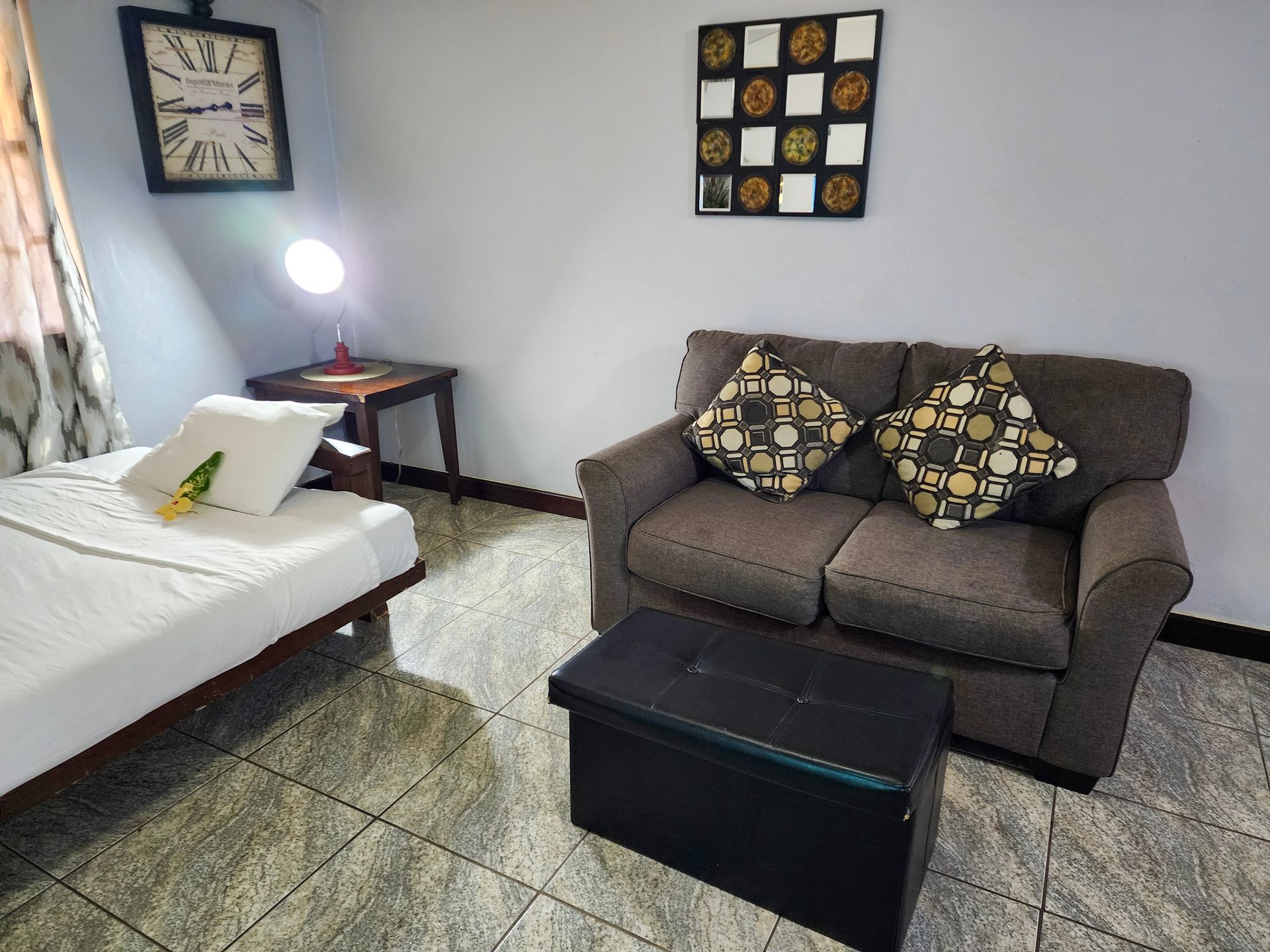 Living area with a couch and a clock on the wall at Caribbean Shores B&B, Family friendly hotel in Hopkins Village.