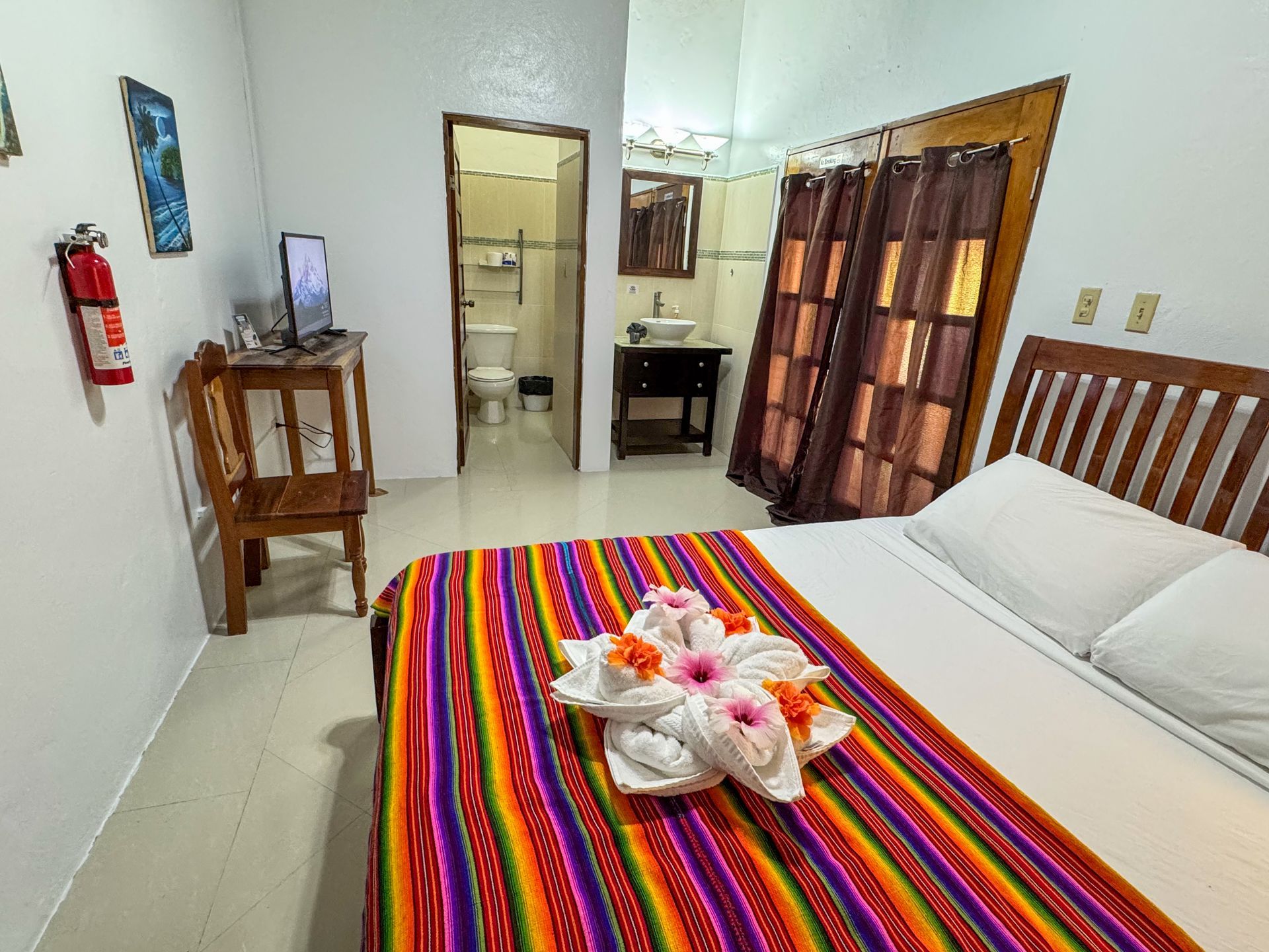 A hotel room with a Queen size bed and a colorful blanket, hotel room in Hopkins Village, Belize
