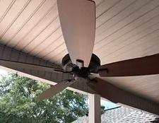 Ceiling fan with five brown blades mounted on a covered porch ceiling