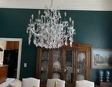 Elegant dining room with dark teal walls, crystal chandelier, and wooden china cabinet