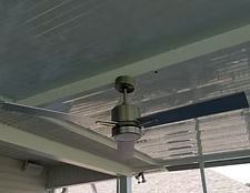 Ceiling fan with white blades mounted on a covered porch ceiling.