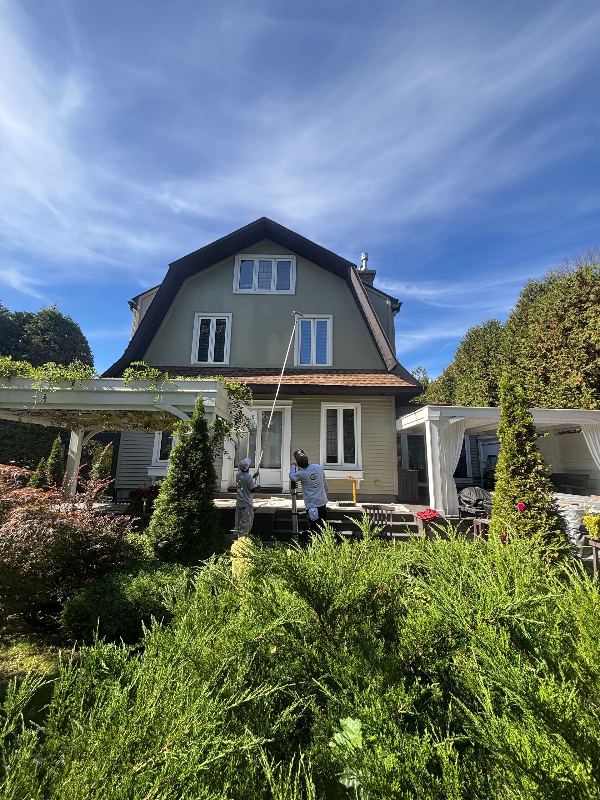 Maison au toit gris et au jardin luxuriant sous un ciel d'un bleu éclatant