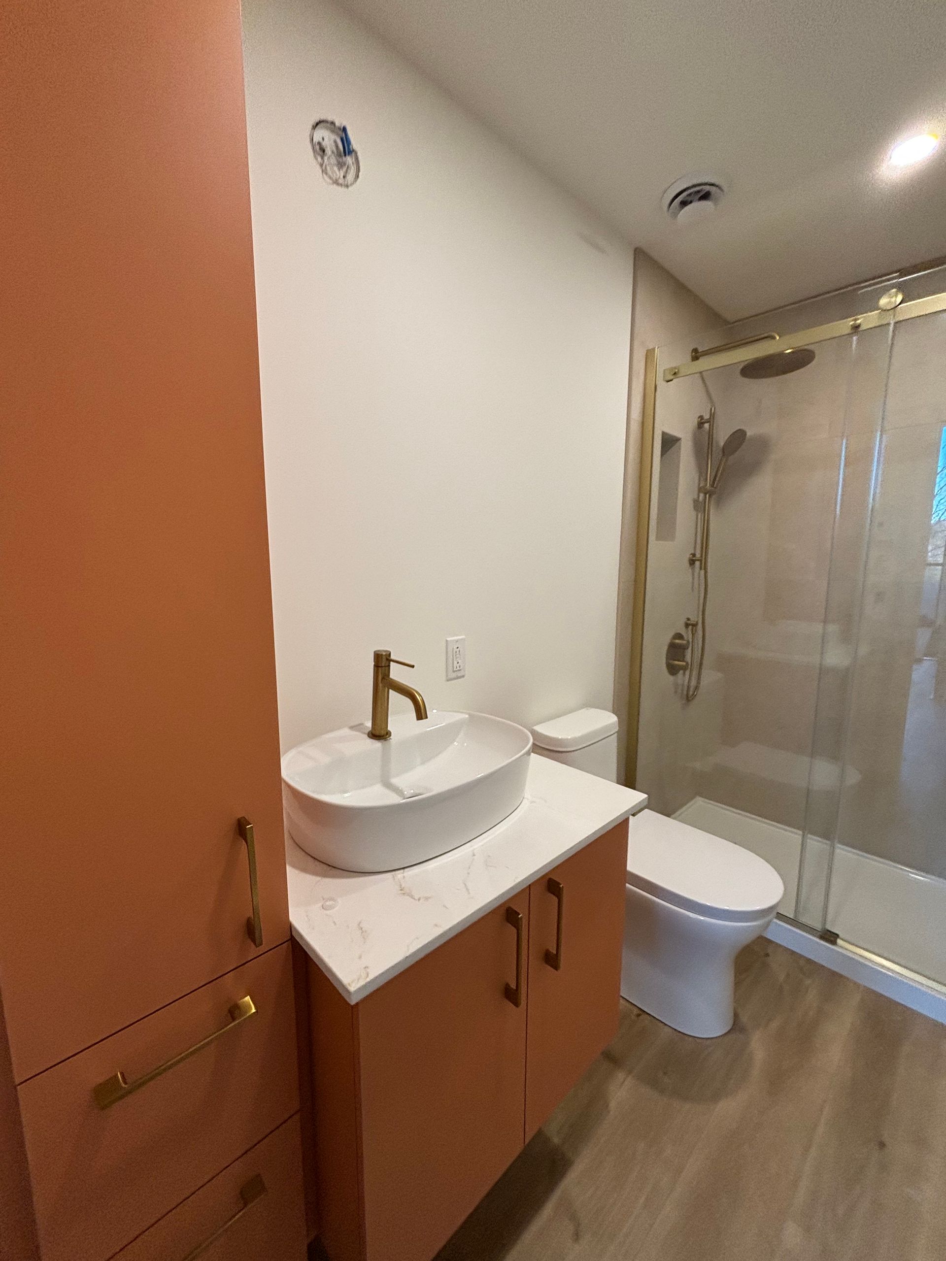 Salle de bains moderne avec meuble-lavabo en bois, lavabo blanc, toilettes et cabine de douche en verre
