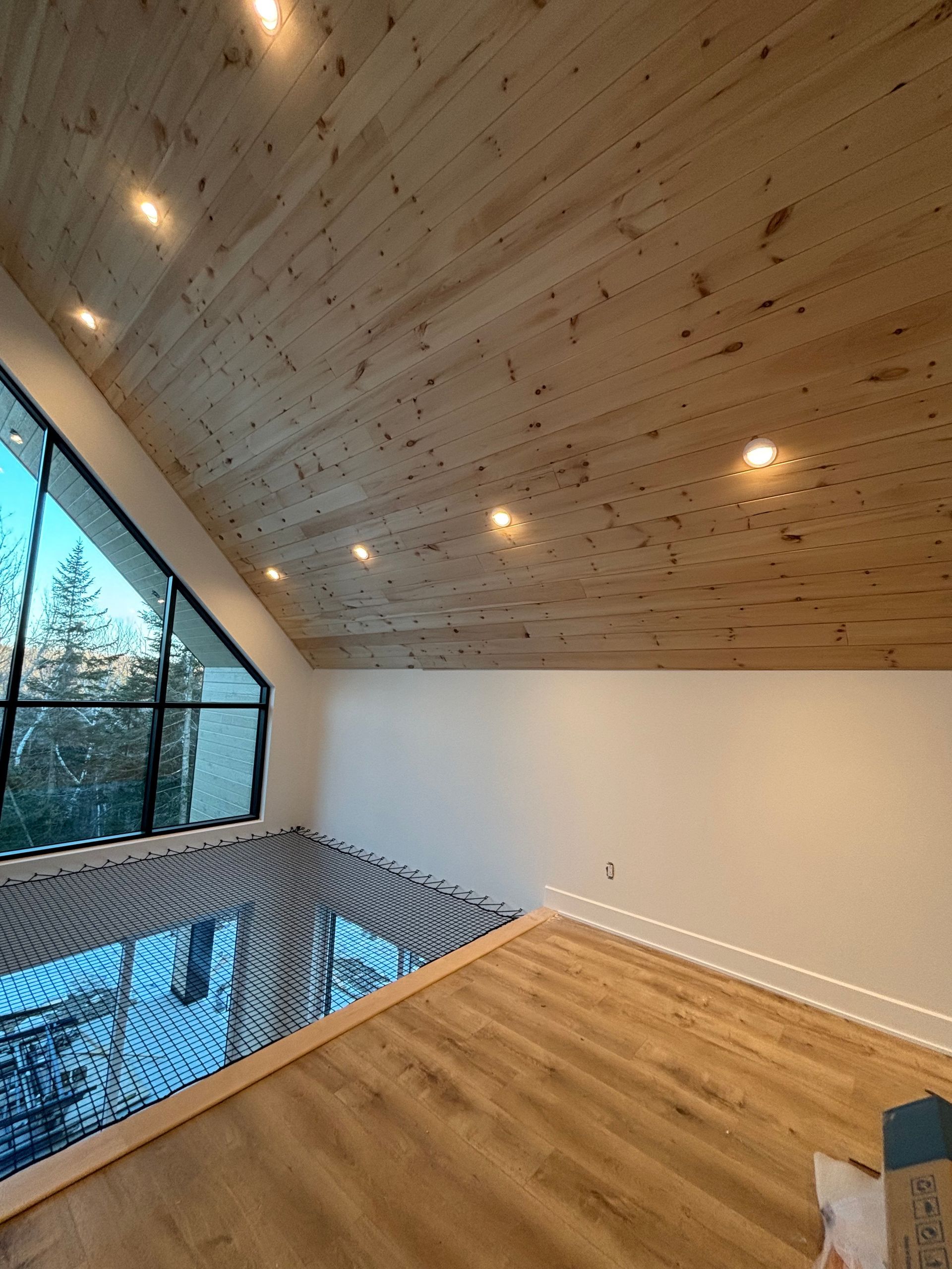 Salle de piscine intérieure moderne avec plafond en bois, grandes fenêtres et parquet donnant sur