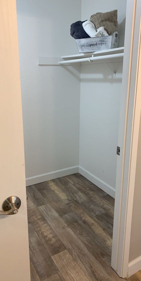 Small closet with a white shelf holding folded items and a gray storage basket.