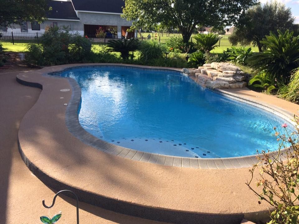 A large swimming pool with a house in the background