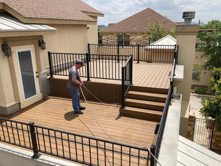 A man is cleaning a deck with a hose.