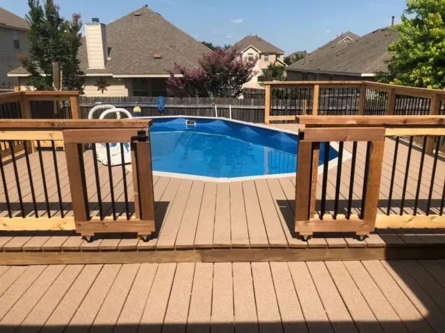 A large swimming pool is behind a wooden deck