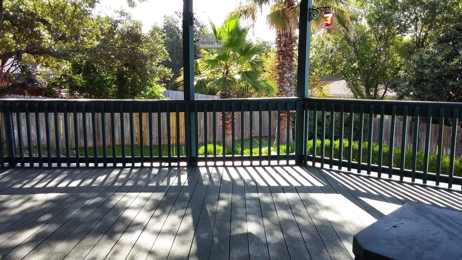 An empty deck with a fence and trees in the background