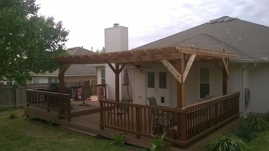 A house with a wooden deck and a pergola on top of it.