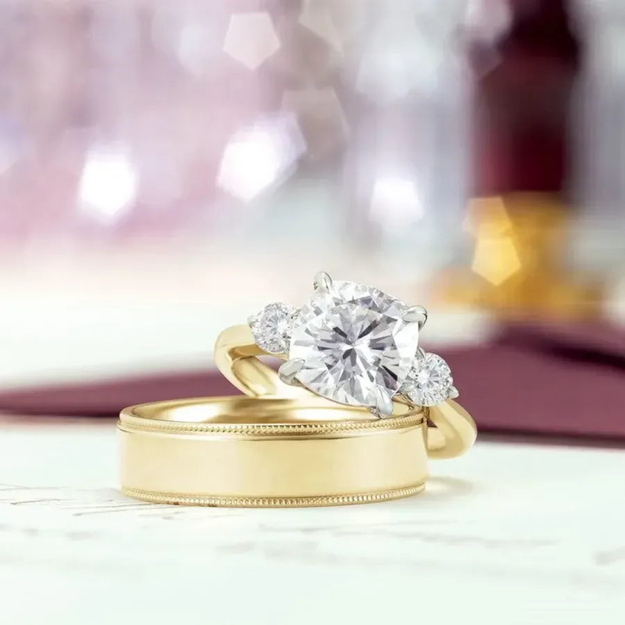 Two gold wedding rings, one with a large diamond and smaller accent stones.