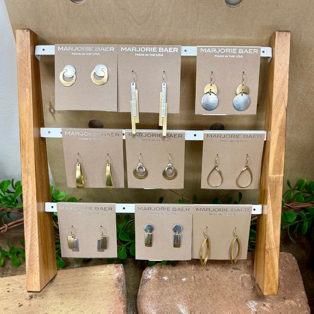 Earring display on a wooden stand. Various gold and silver earrings on brown cards.