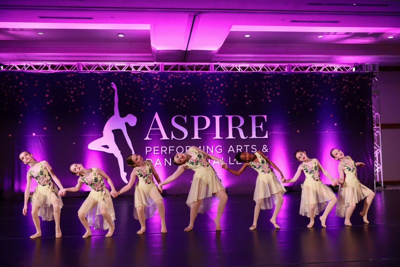 Dancers performing on a purple-lit stage at Aspire Performing Arts competition