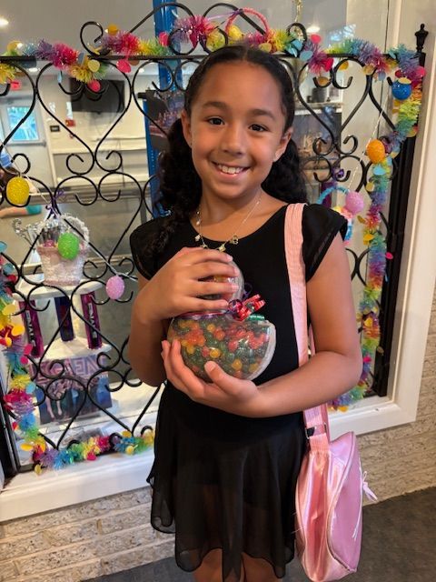 Smiling child holding a colorful jar of beads in front of a decorative display wall