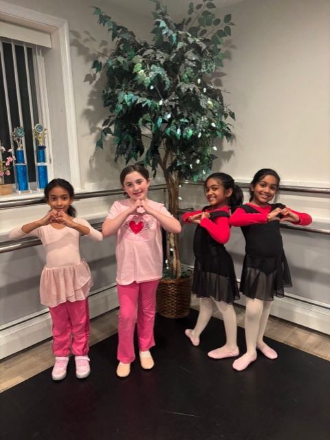 Four children in dance outfits posing in a studio with a large potted tree backdrop.