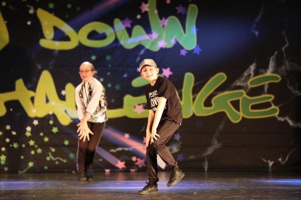 Two dancers performing onstage in front of colorful graffiti-style backdrop