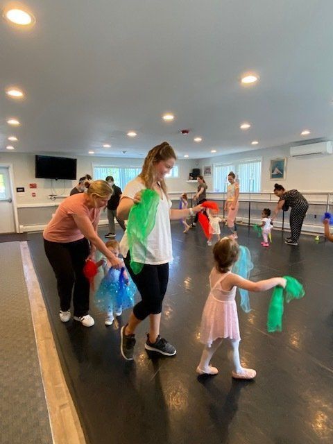 People dancing with colorful scarves in a bright studio room