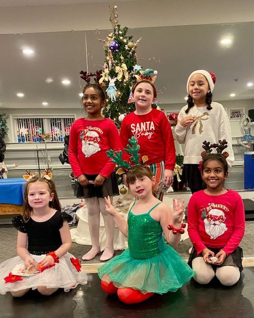 Children in festive holiday outfits posing in front of a Christmas tree indoors