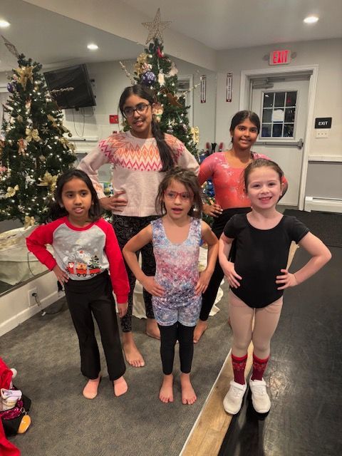 Five children posing in a holiday-decorated room with two Christmas trees.