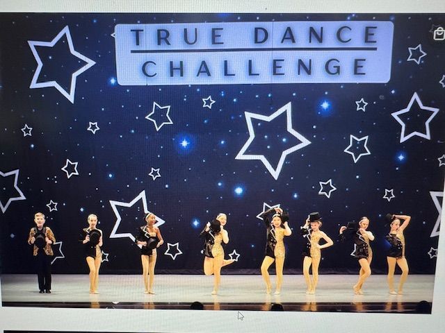 Dance troupe performing on stage under a “True Dance Challenge” banner with star decorations