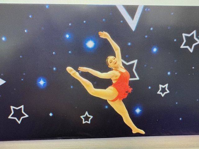 Ballet dancer in a red costume leaps against a starry black background