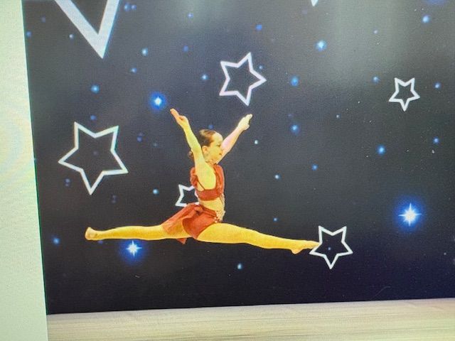 Gymnast performing a split leap against a starry black backdrop