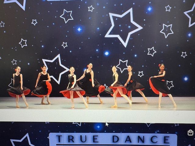 Five dancers in black and red costumes performing on a starry stage with “TRUE DANCE” sign.