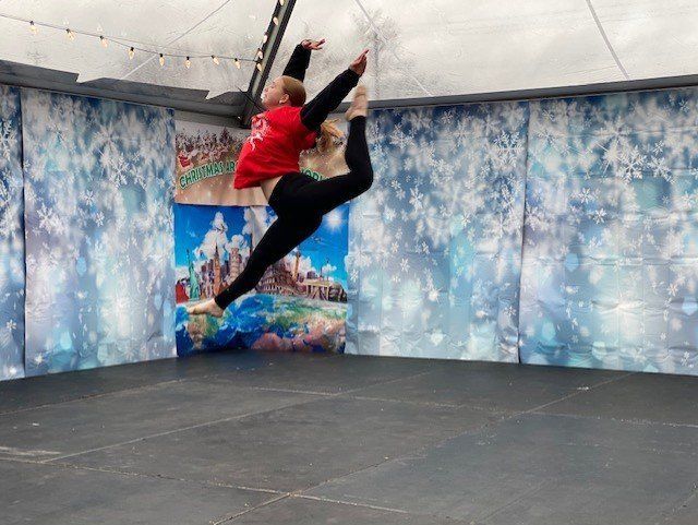 Two people mid-jump in a trampoline room with blue wall mural and black padded floor