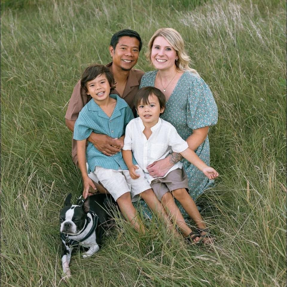 Family of four and a dog posing in tall grass, smiling outdoors
