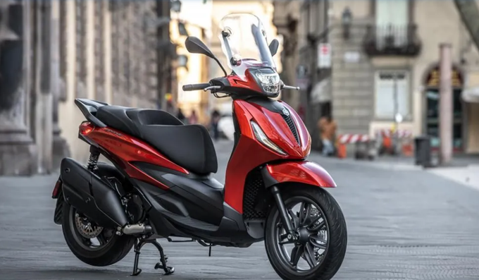 Scooter Piaggio Beverly rosso parcheggiato su una strada cittadina.