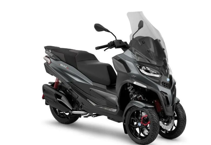 Scooter a tre ruote Piaggio MP3 grigio con parabrezza, parcheggiato su sfondo bianco.