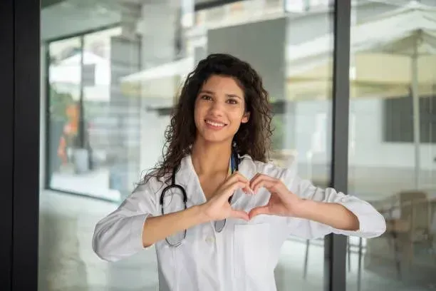 A female doctor is making a heart shape with her hands.