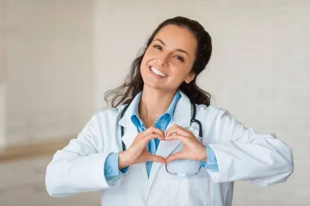 A female doctor is making a heart shape with her hands.