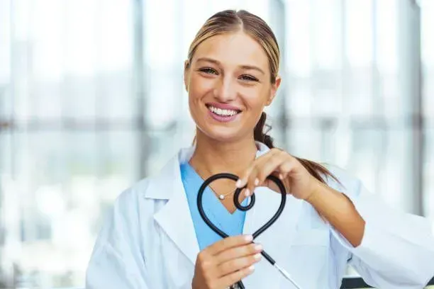A female doctor is holding a stethoscope in the shape of a heart.