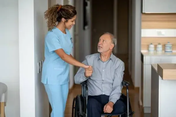 A nurse is helping an elderly man in a wheelchair.