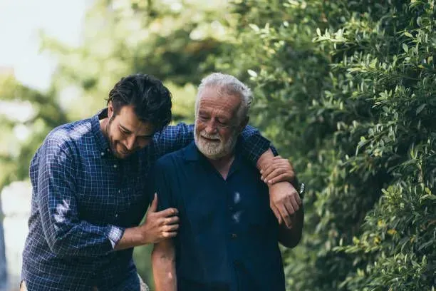 A young man is helping an older man walk.