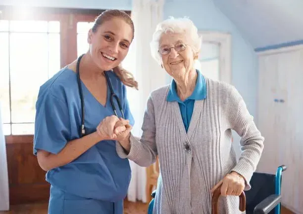 A nurse is helping an elderly woman in a wheelchair.