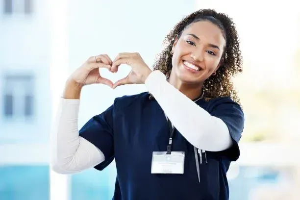 A nurse is making a heart shape with her hands.